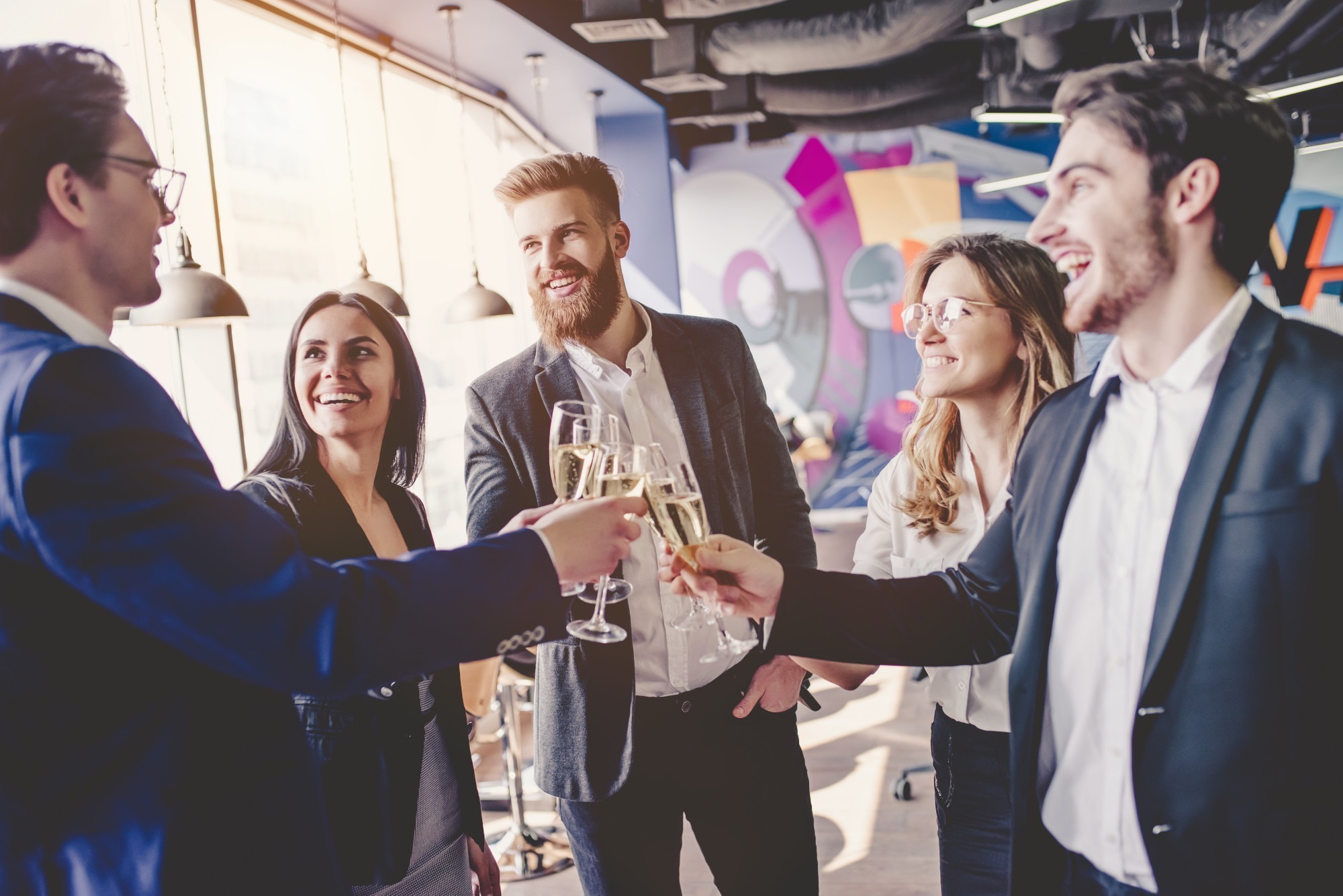 Group of young business people are working together in modern office. Successful team in coworking are celebrating at a corporate event with champagne. Freelancers. Music and MC services Pinnacle Moments DJ Services Toledo Ohio